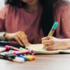 ノートに英語学習の内容を書き込む女性